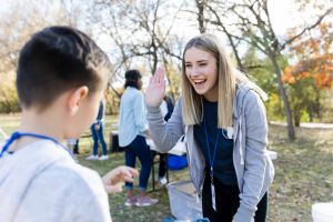 Lady outside talking to a boy saying hello