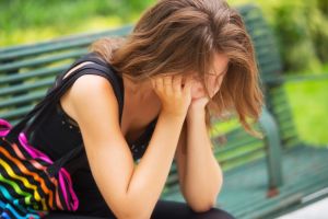 Girl on a park bench looking upset.