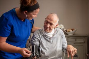 Older man and a nurse helping him.