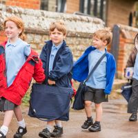 Children in a queue with coats and school uniforms on.