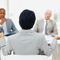 Somebody being interviewed in front of a panel of people.