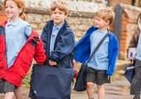 Children in a queue with coats and school uniforms on.